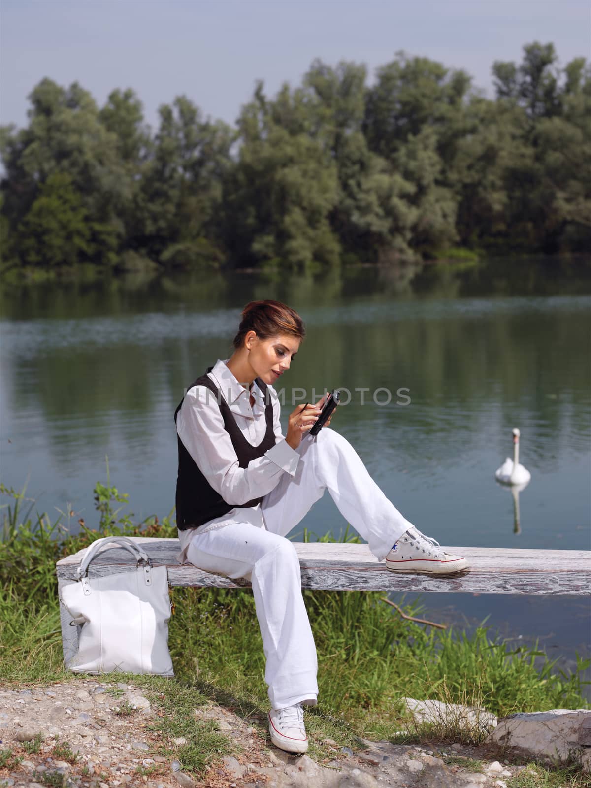 Beautiful young woman using PDA outdoors 