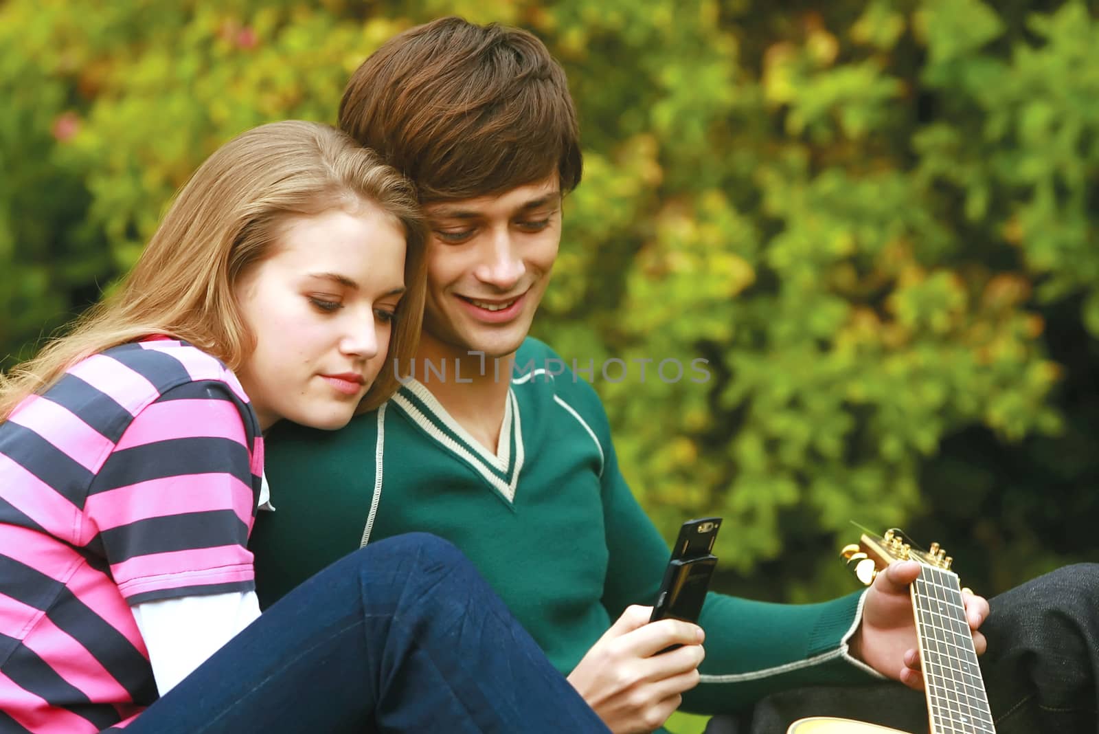 Romantic young couple relaxing outdoors in park smiling 