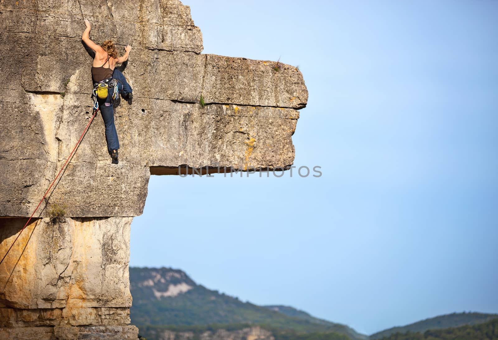 Young female rock climber a face of a cliff
