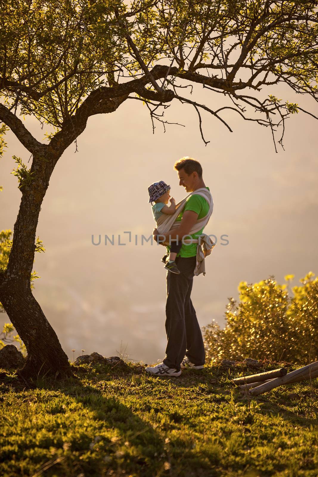 Father carrying his son in sling by photobac