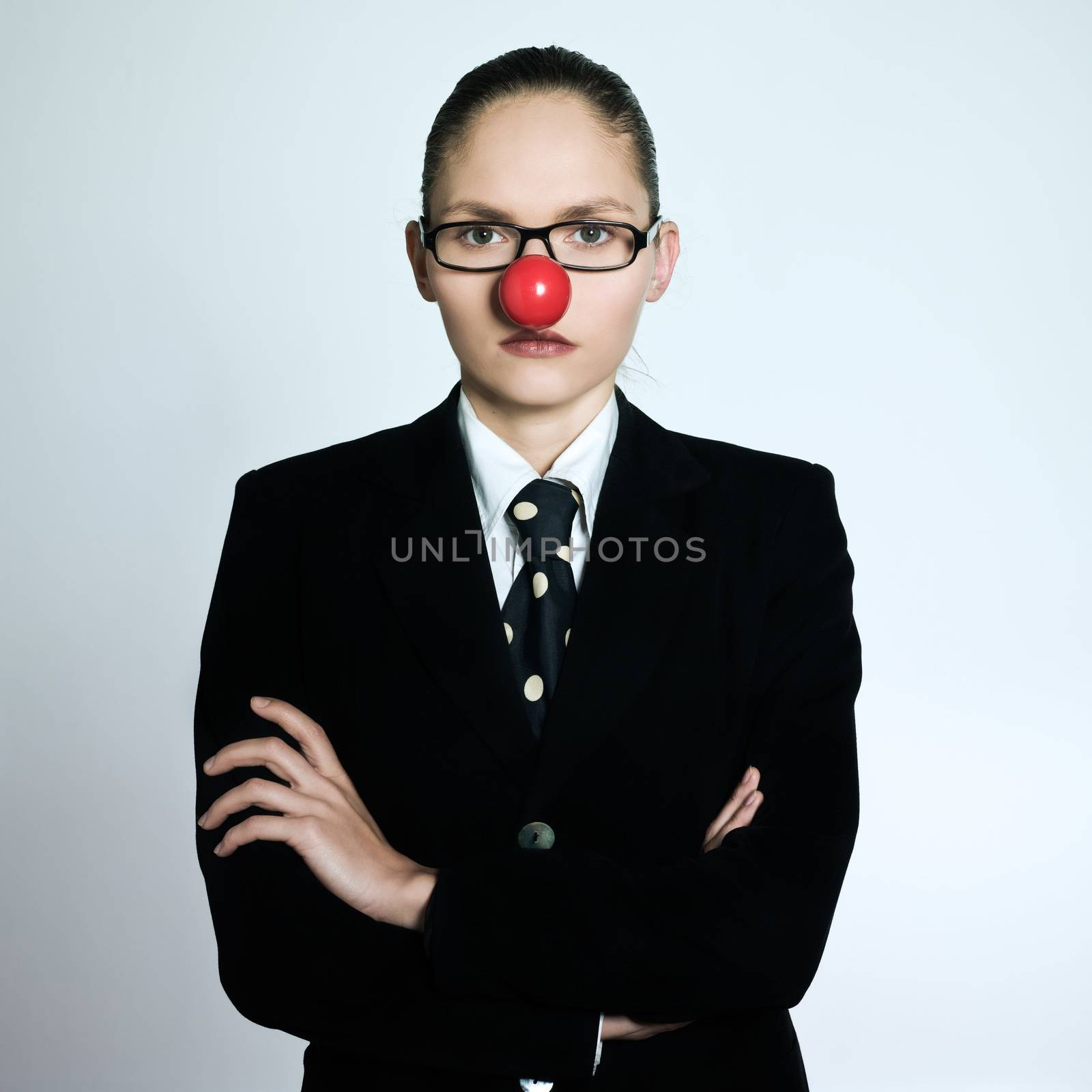 studio shot portrait of one caucasian one young business woman with a clown nose on isolated grey background