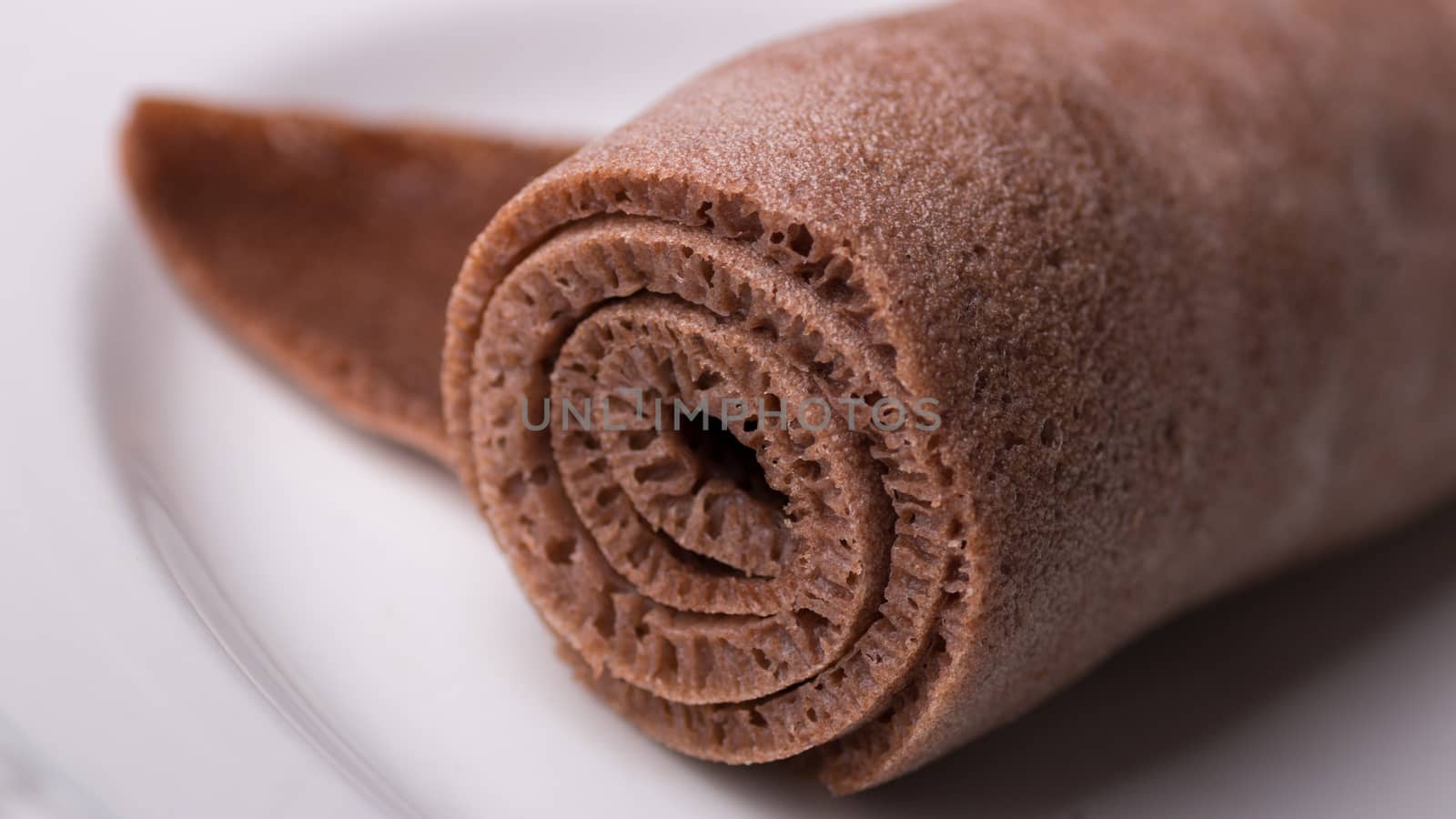 A Roll of Injera made from black teff on a white plate