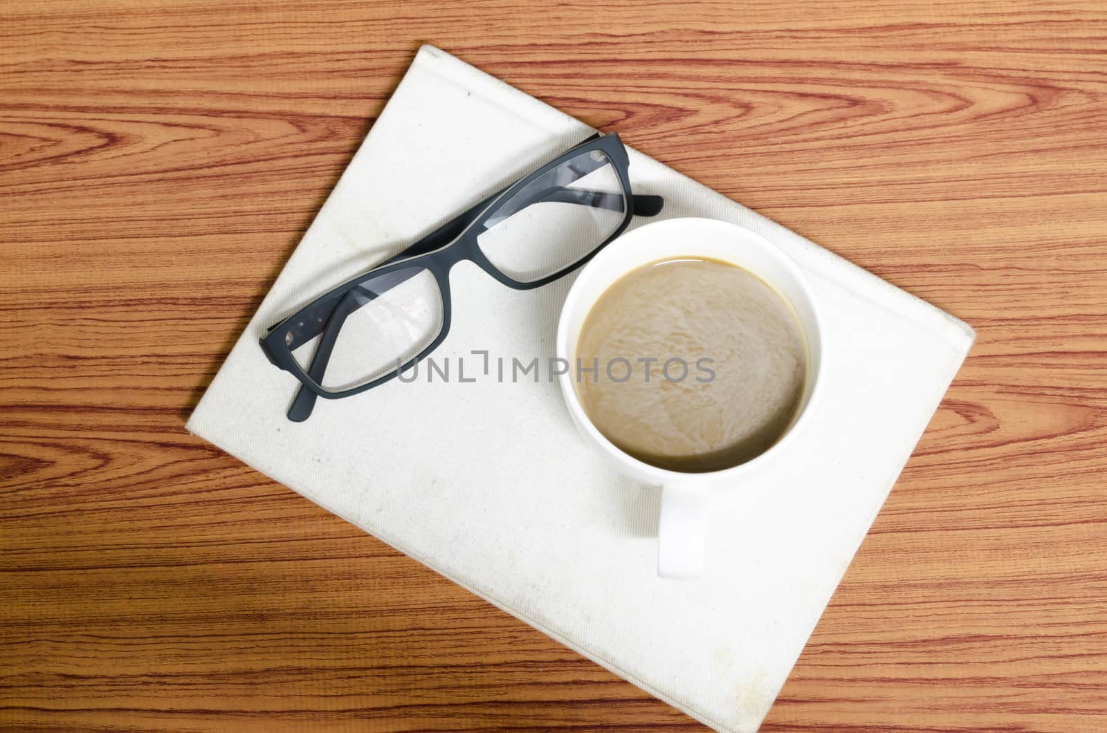 coffee cup and notebook with glasses on wood background