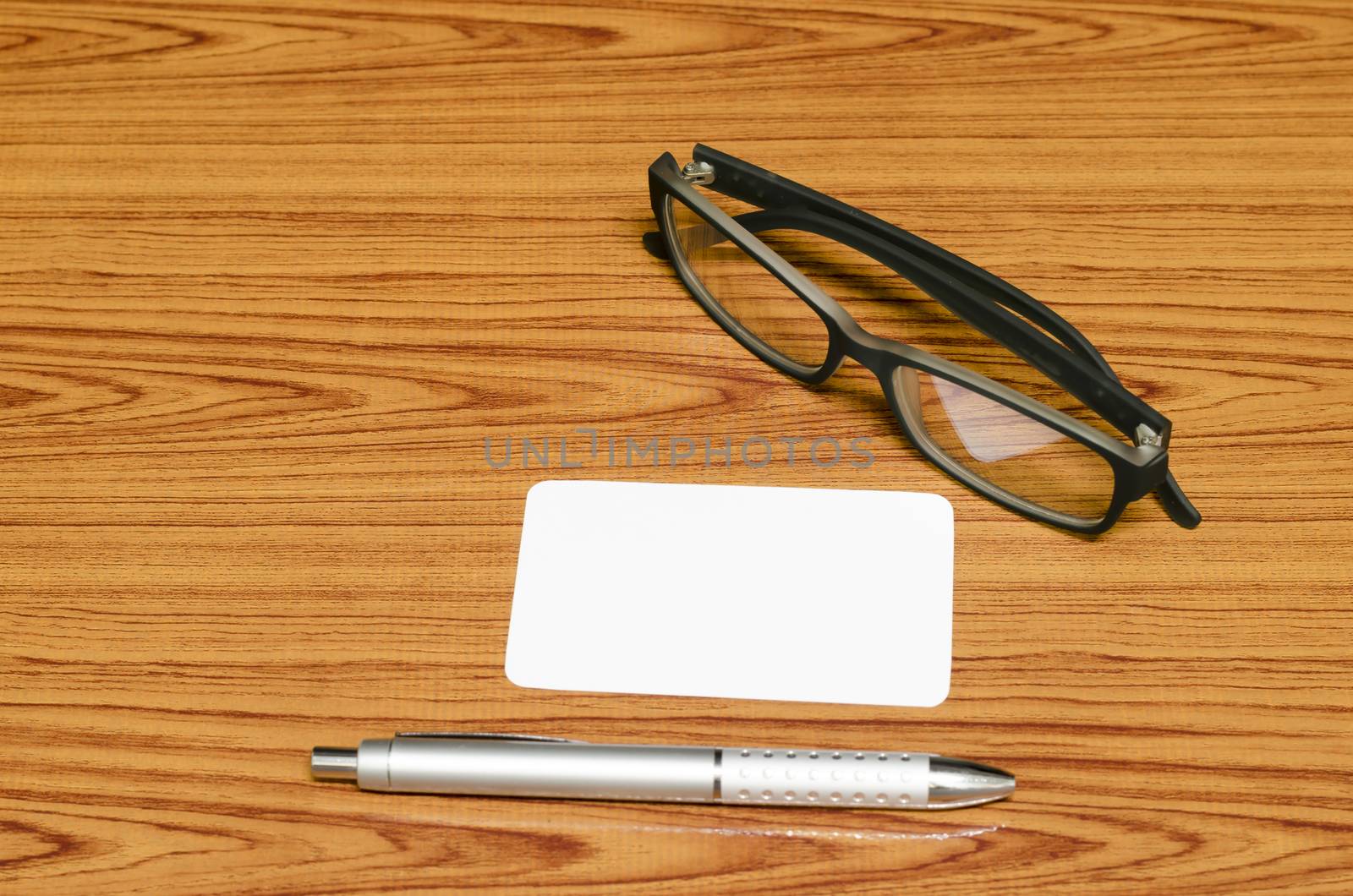 business card and pen with glasses on wood background