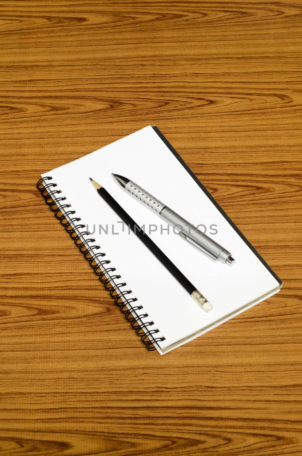 notebook pen and pencil on wood background