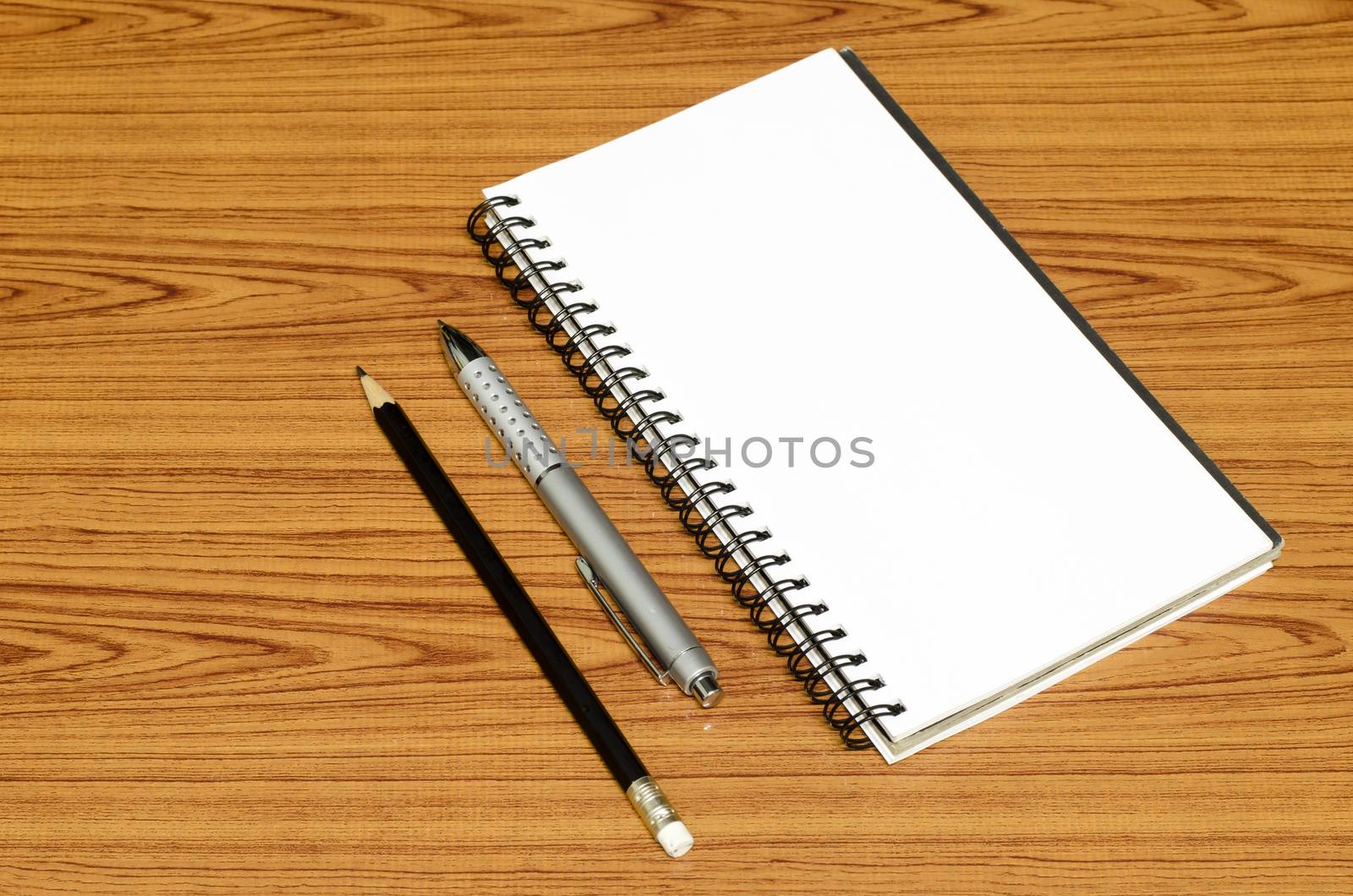 notebook pen and pencil on wood background