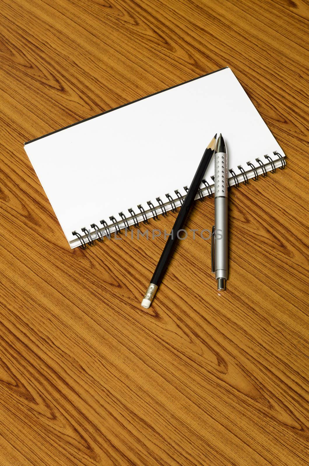 notebook pen and pencil on wood background
