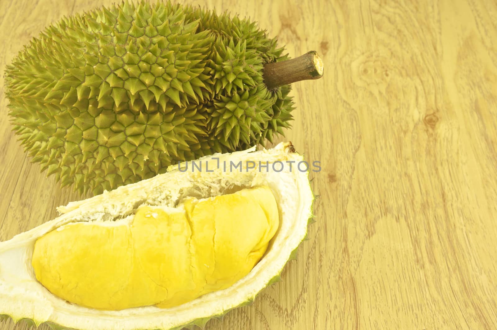 Green durian ripe and part with spikes on wood background.