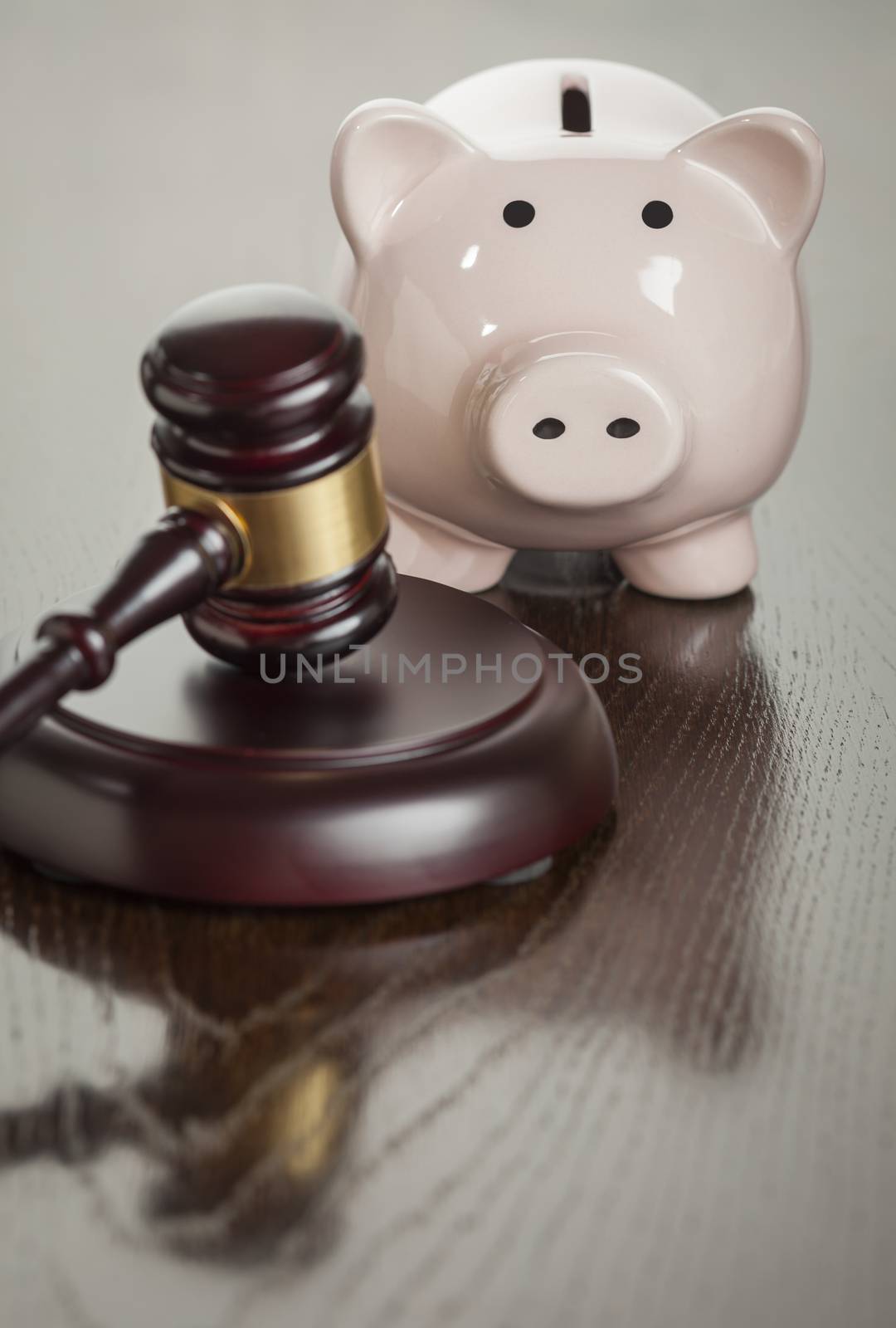 Gavel and Piggy Bank on Reflective Wooden Table.