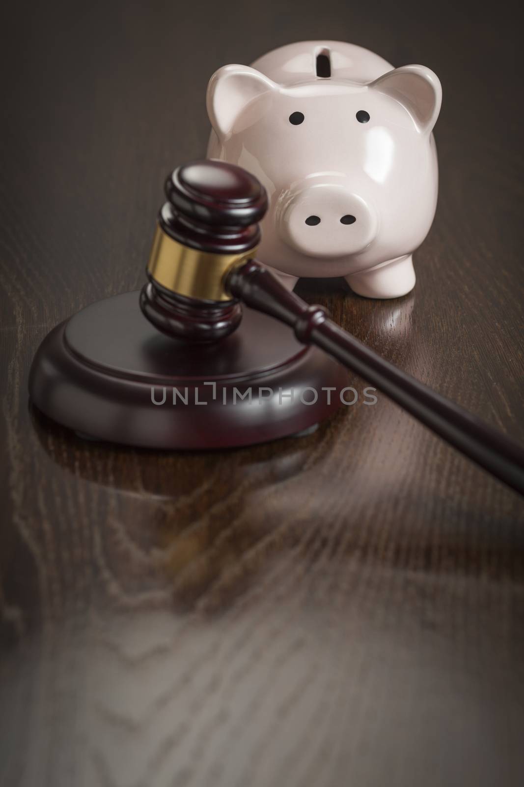 Gavel and Piggy Bank on Reflective Wooden Table.