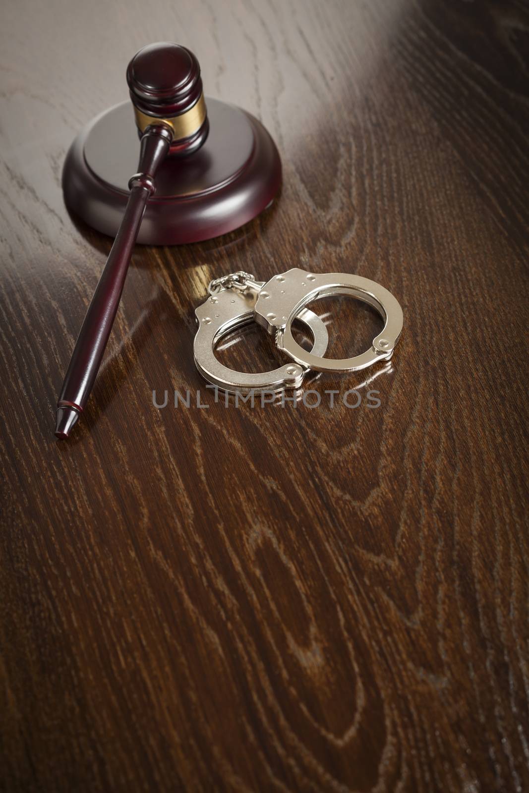 Gavel and Pair of Handcuffs on Wooden Table.