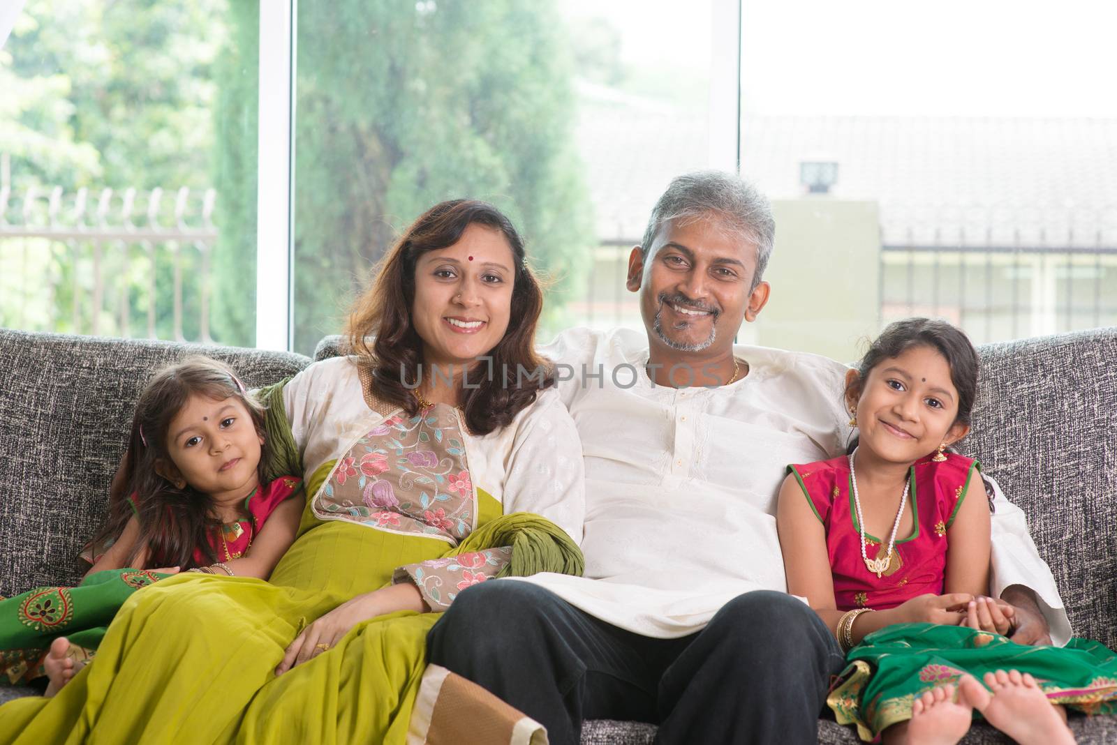 Indian family at home. Asian parents and children living lifestyle, sitting on couch indoor smiling happily.
