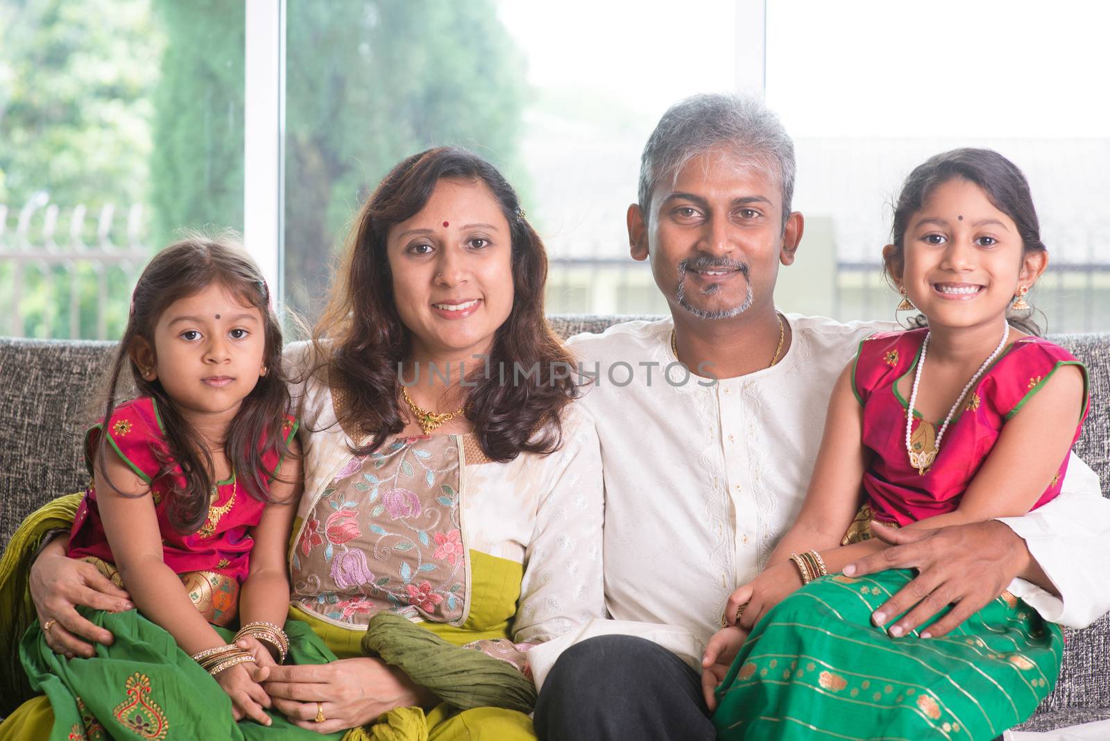 Happy Indian family at home. Asian parents and children living lifestyle, sitting on couch indoor happily.