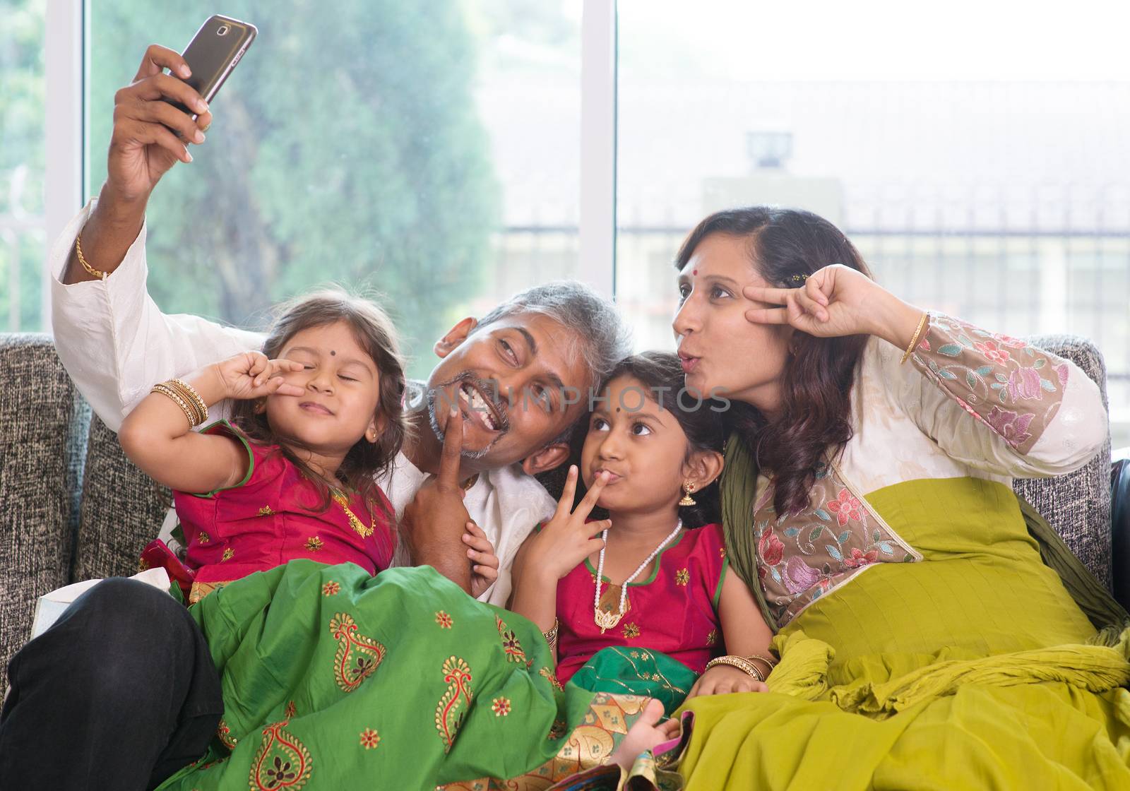 Asian Indian family selfie or self photograph at home. Parents and children indoor lifestyle.