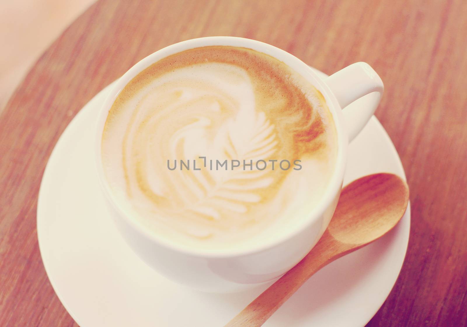 Cup of latte or cappuccino coffee with wooden spoon, retro filter effect