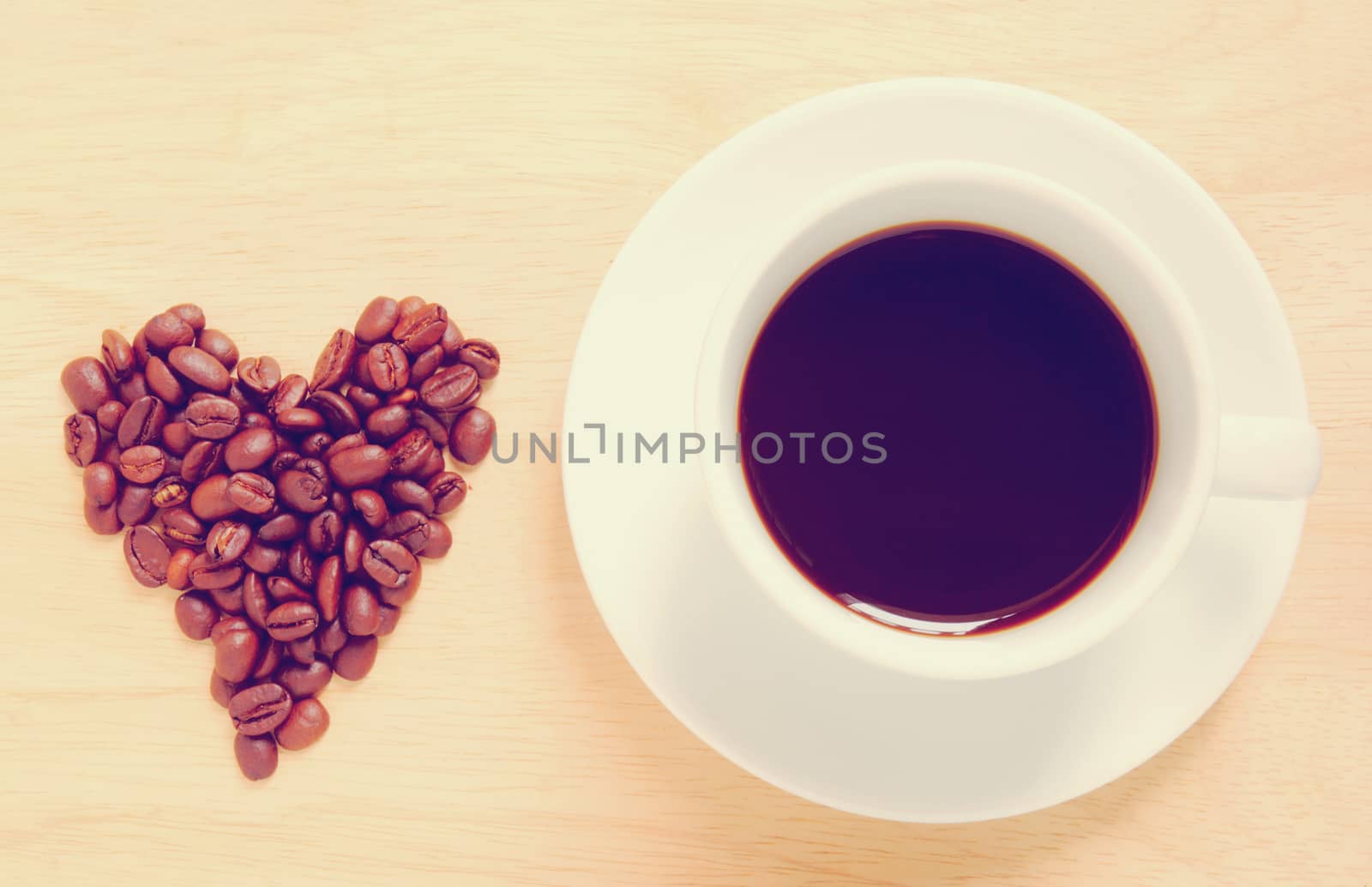 Heart shape made from coffee beans with a cup of coffee, retro filter effect