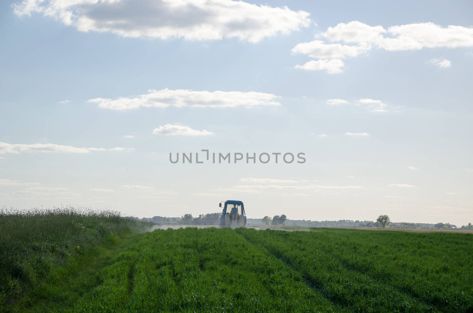 Tractor spray field with chemicals and worker man by sauletas