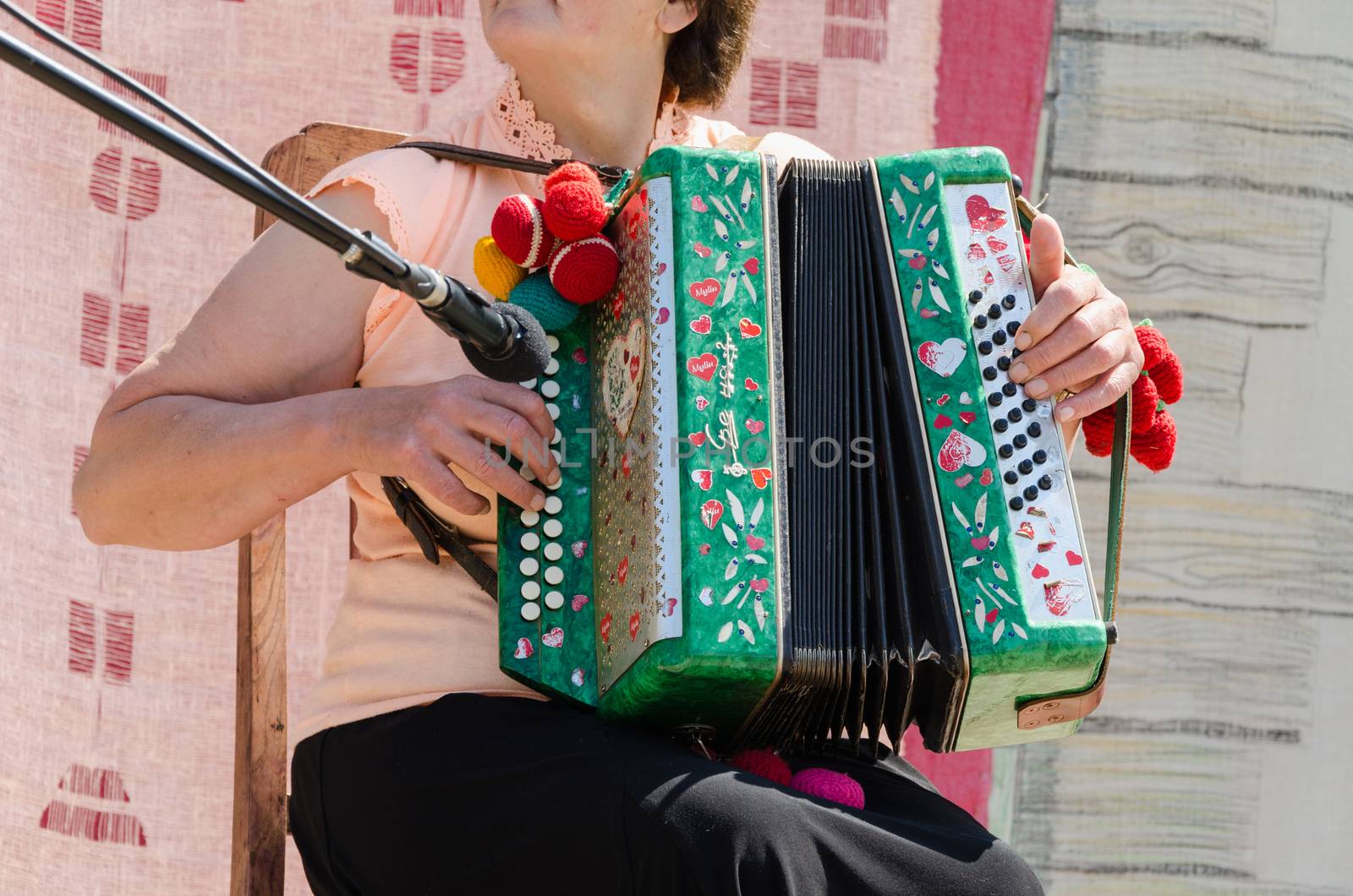 BIRZAI, LITHUANIA - JUNE 08: the woman musician at the microphone in chair fast finger movements stamp accordion buttons on June 08, 2013 in Birzai.