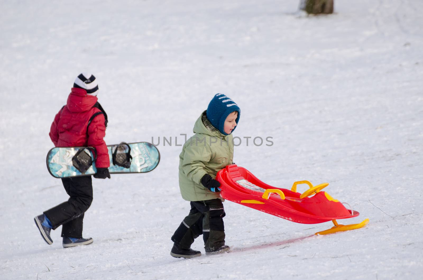 children with snowboard and sledge with handlebar by sauletas