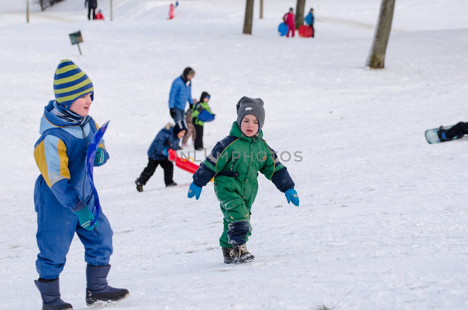 VILNIUS, LITHUANIA - JANUARY 18: two boy climb uphill with waterproof coverall on January 18, 2014 in Vilnius, Lithuania. Seasonal winter time fun outdoor