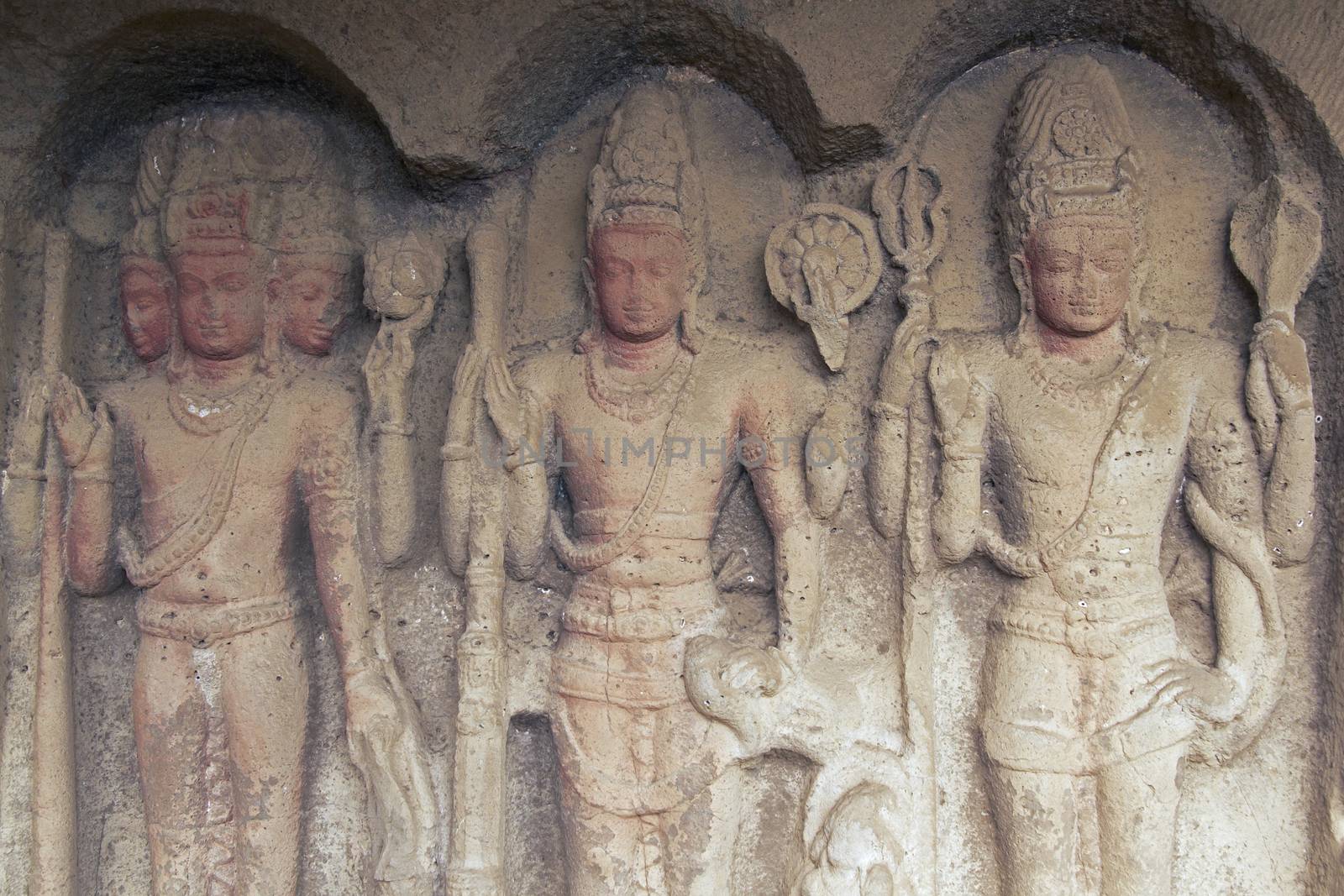Images of the Hindu gods Brahma Vishnu and Shiva carved into solid rock inside an ancient cave temple Ellora Caves near aurangabad India.