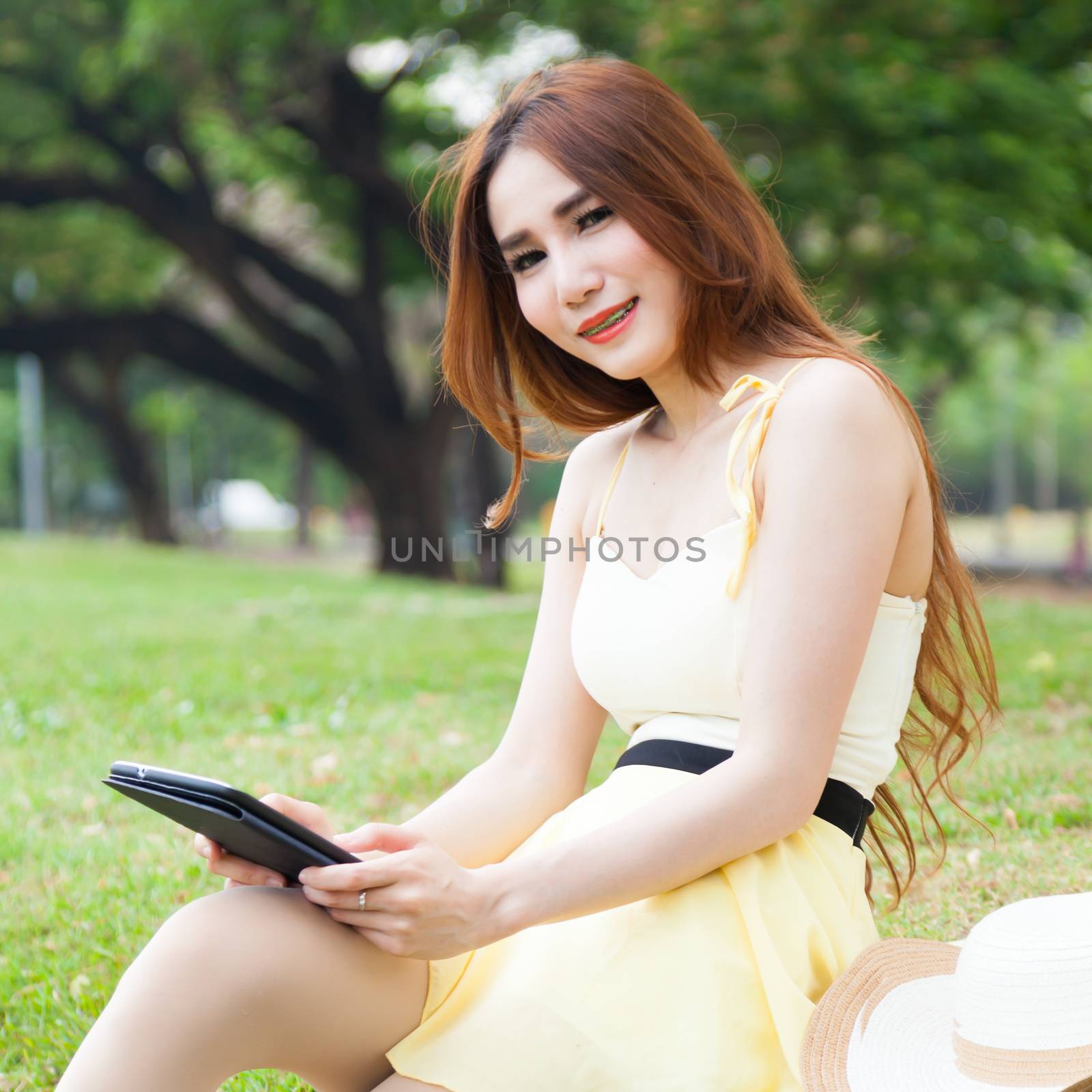 Woman sitting on lawn holding tablet. by a454