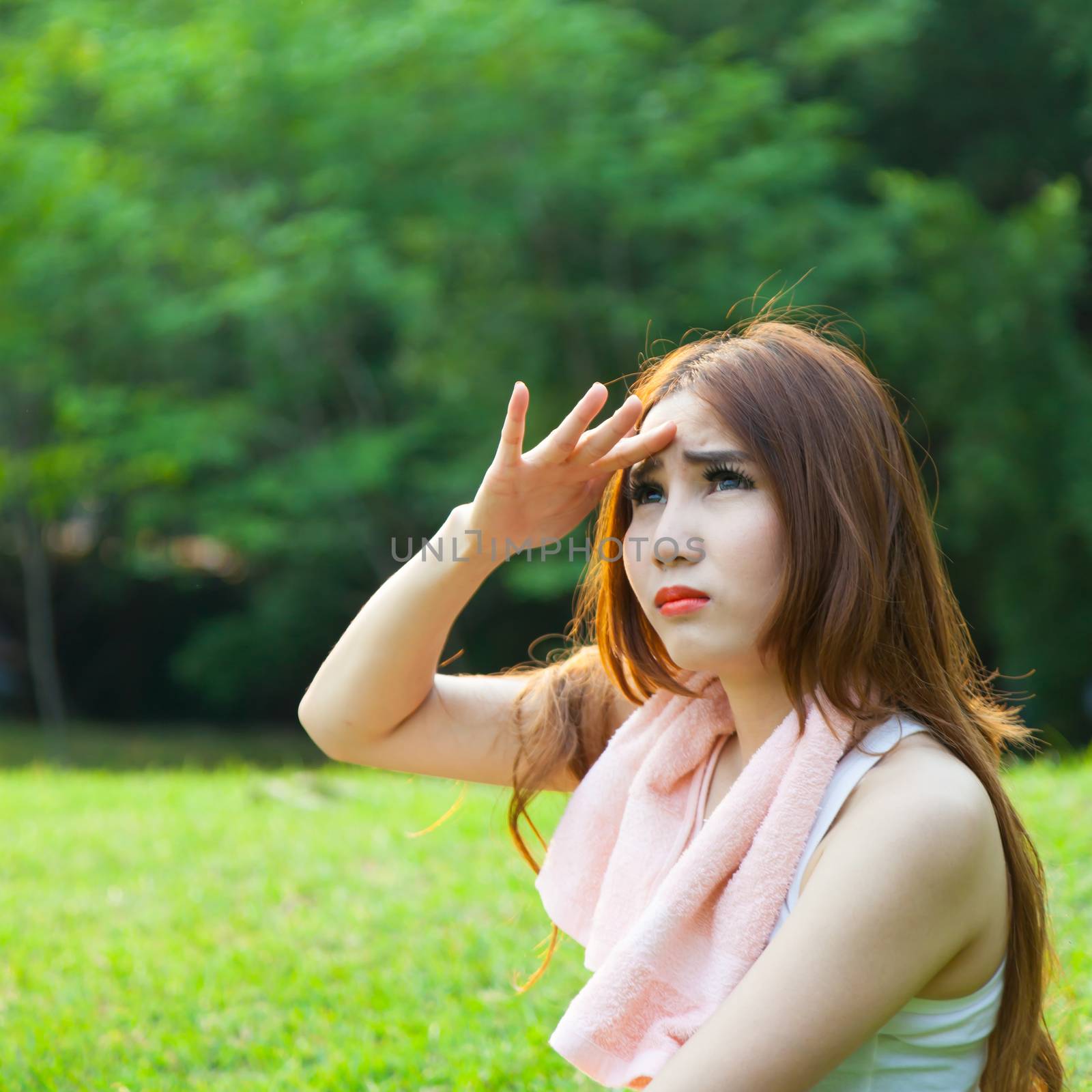 Woman is sitting a break from exercise. Sitting on the grass in the park.