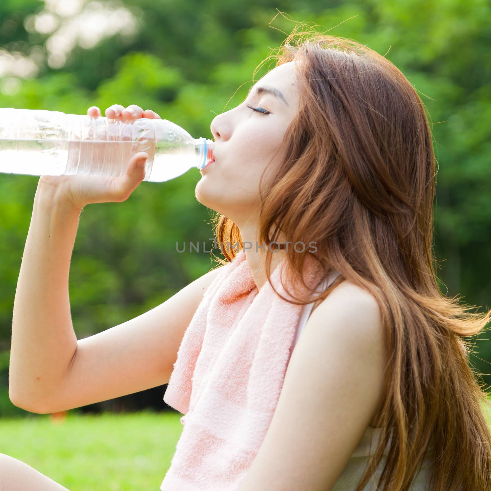 Woman sitting tired and drinking water after exercise. by a454