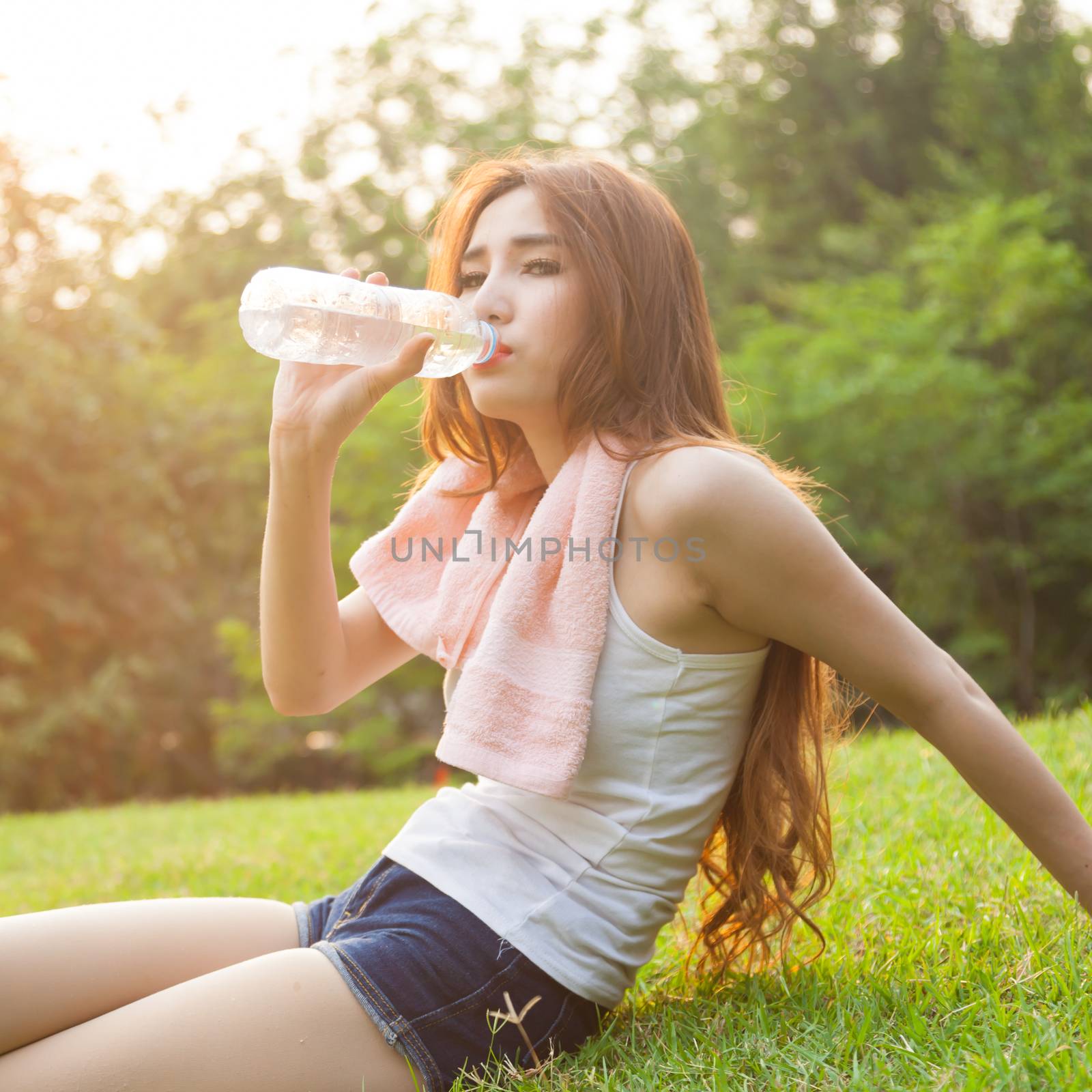 Woman sitting tired and drinking water after exercise. by a454