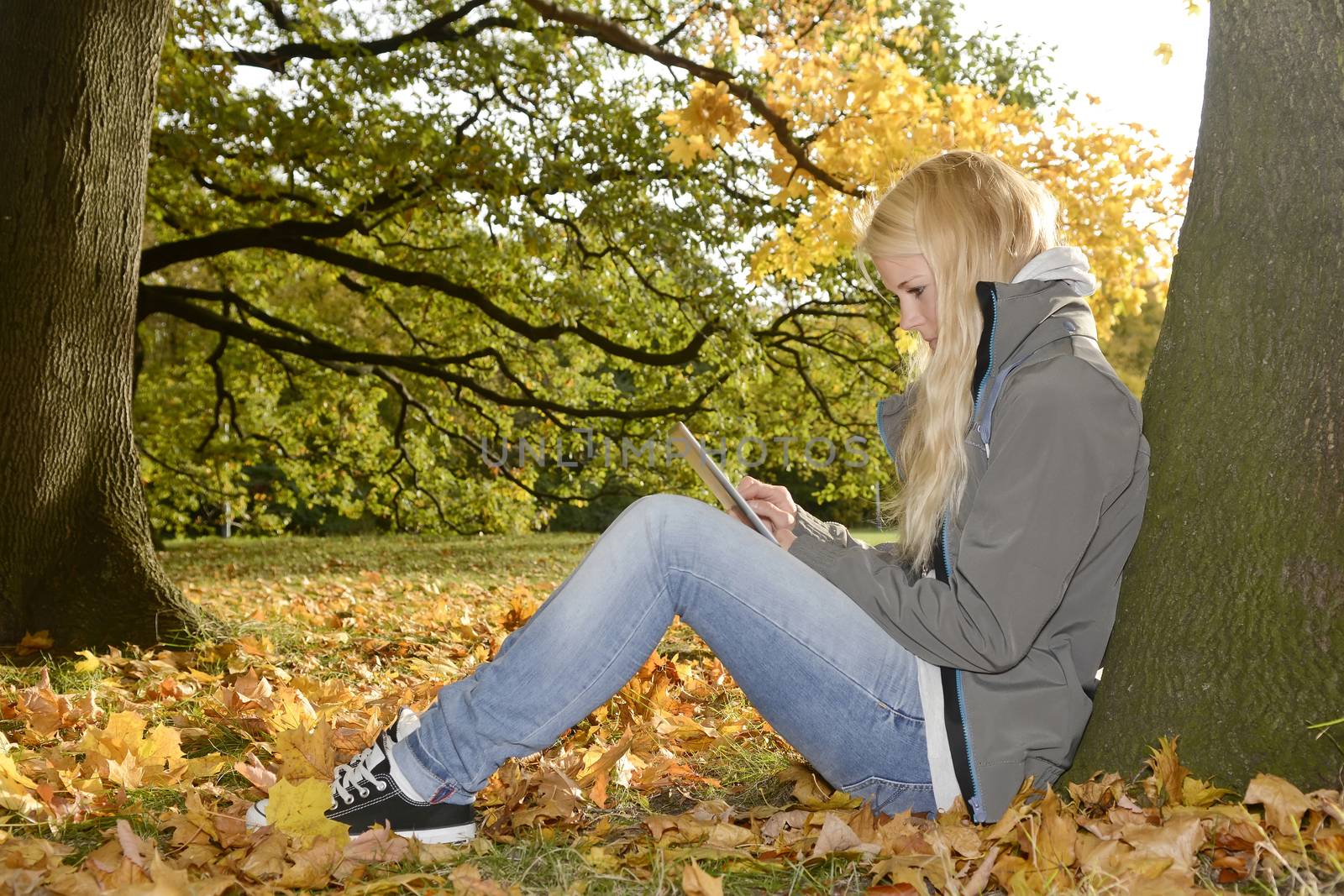 young woman with digital tablet in autumn park