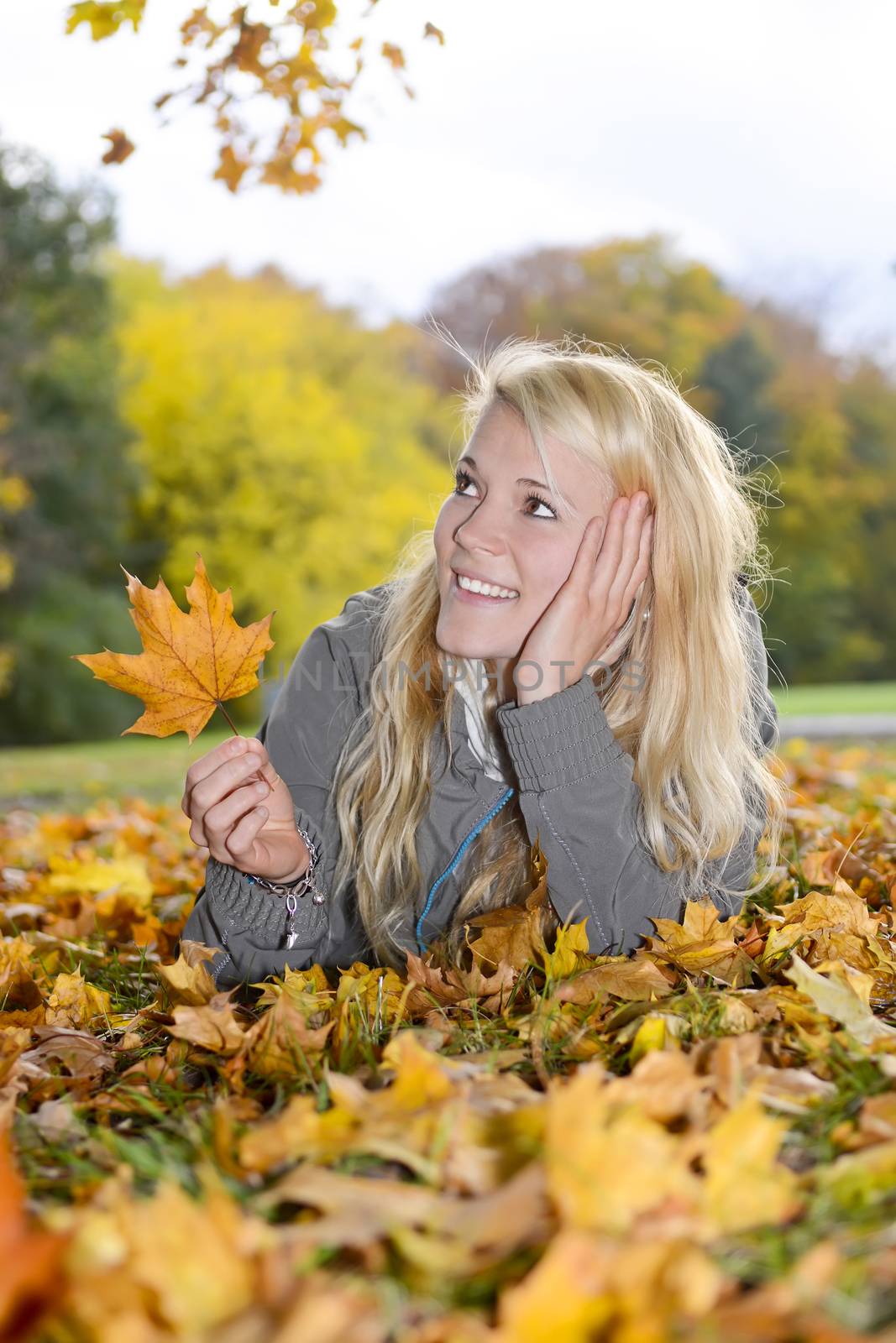 pretty woman with autumn leave lying on a meadow