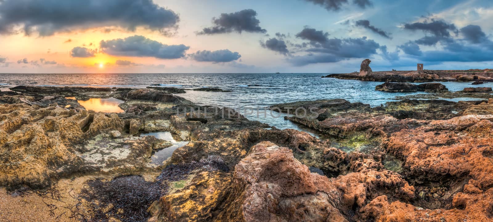 sunset over the sea and rocky coast with ancient ruins