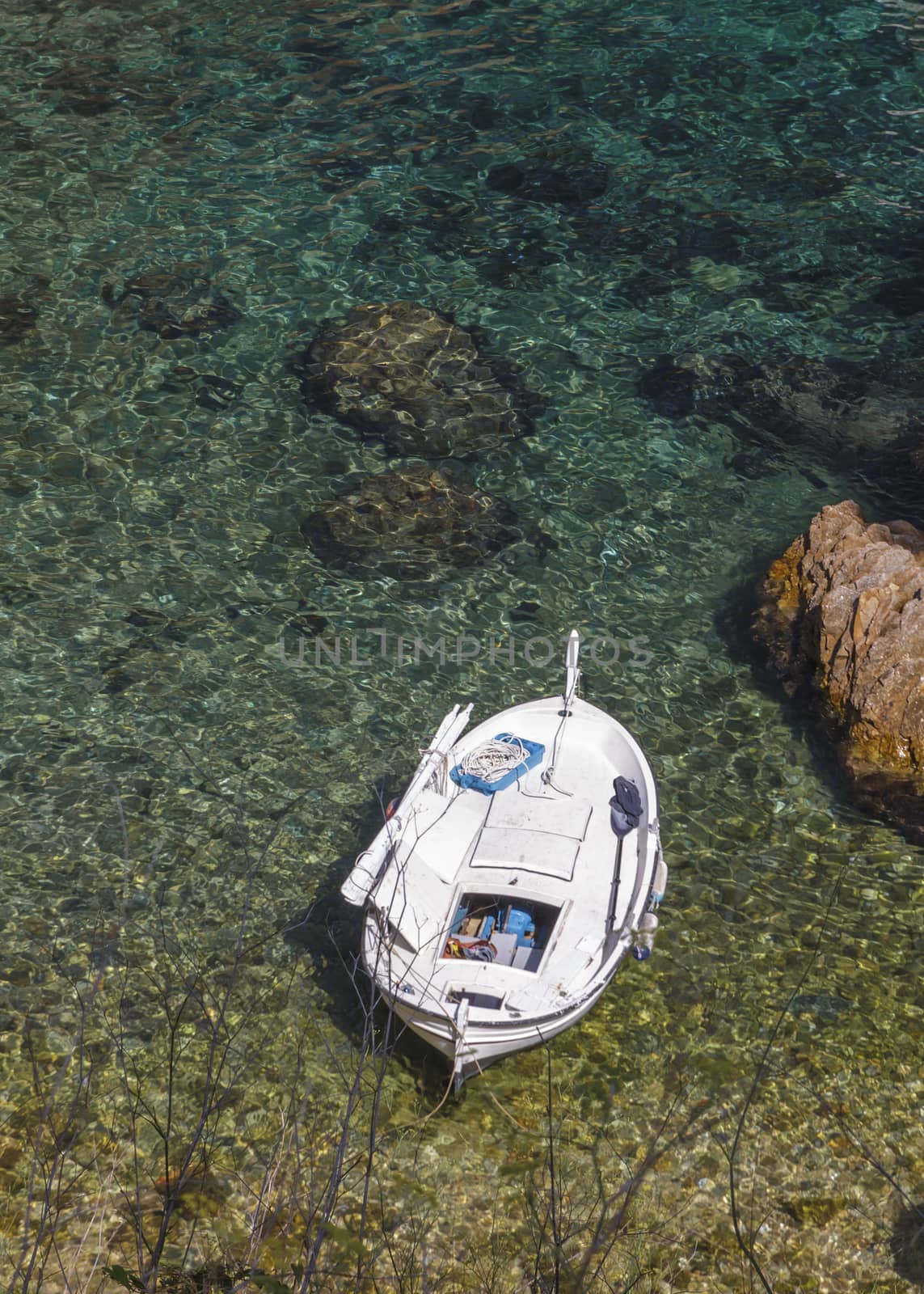 Aerial view of a small traditional fishing boat, moored in a rocky cove of the Costa Brava