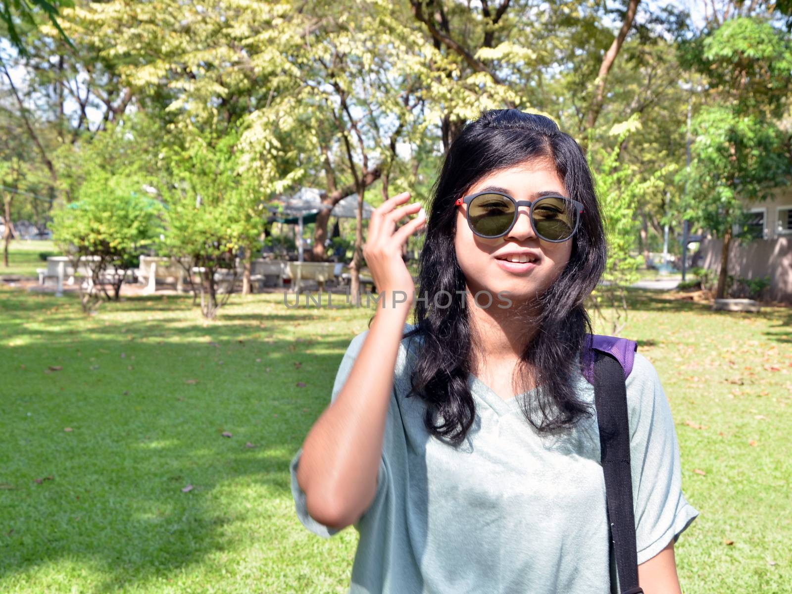 Young woman looking at camera through sunglasses by siraanamwong