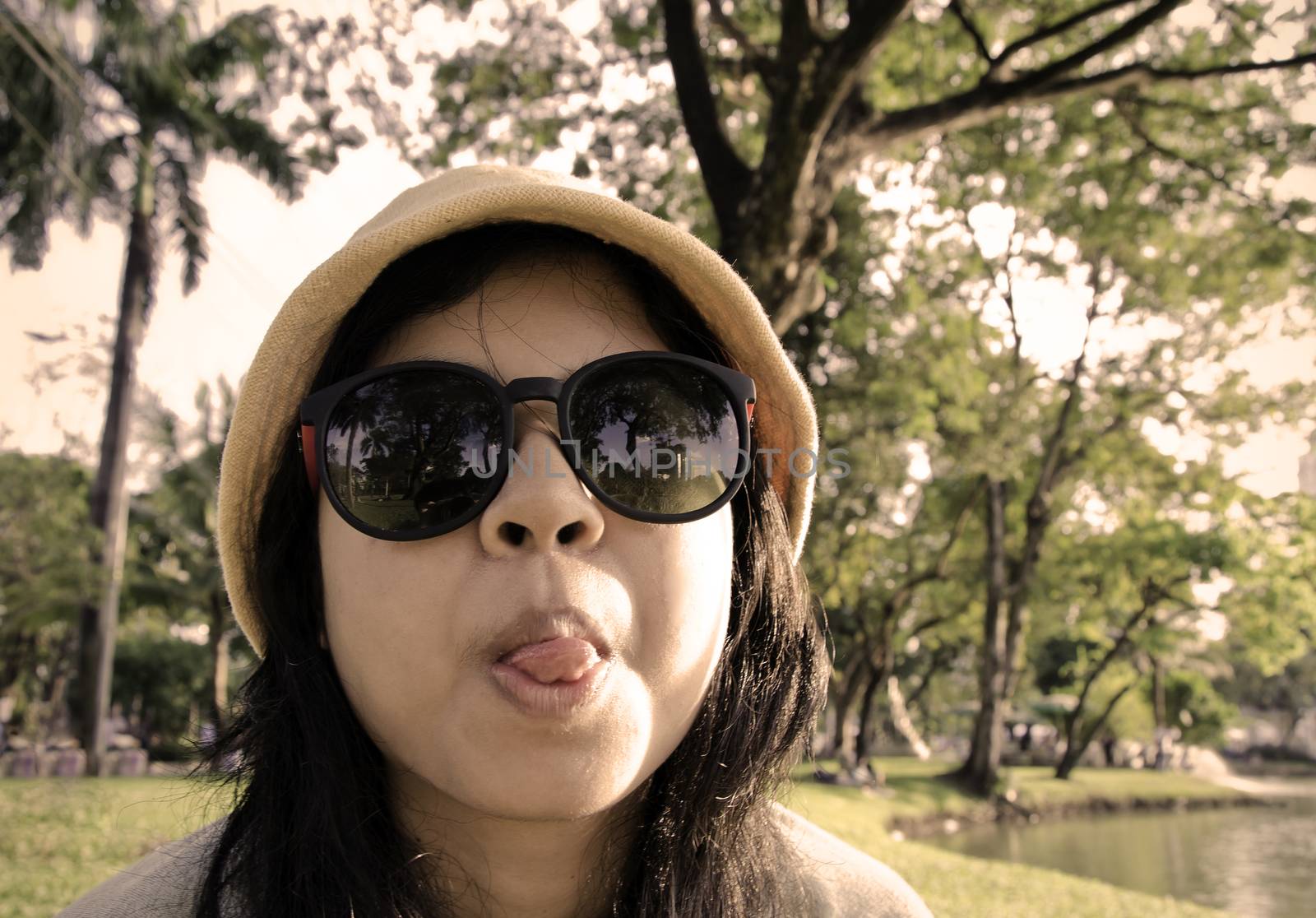 Young naughty woman looking at camera through sunglasses by siraanamwong