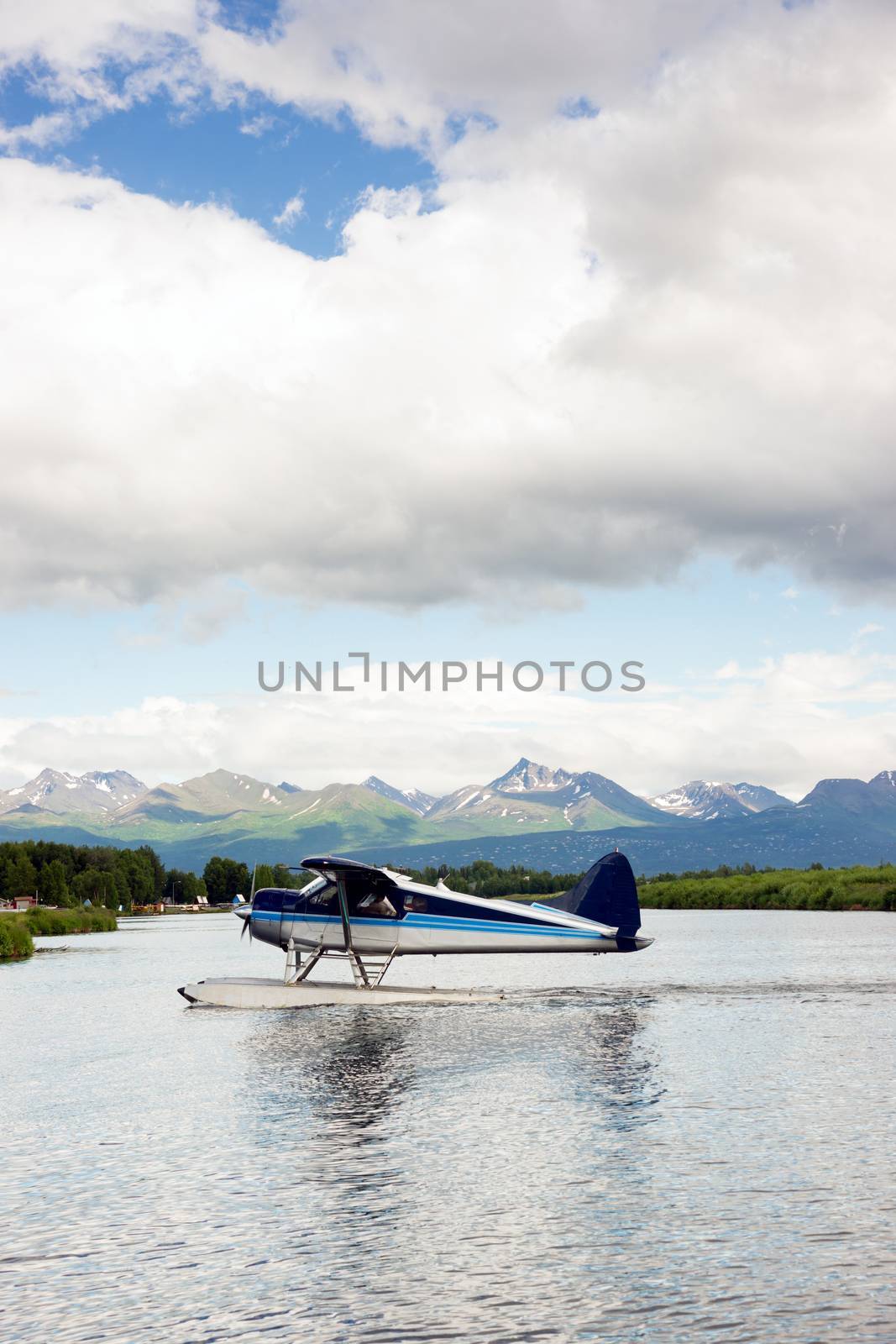 A bush plane performs take off in Alaska with Chugach Mountains in the Background