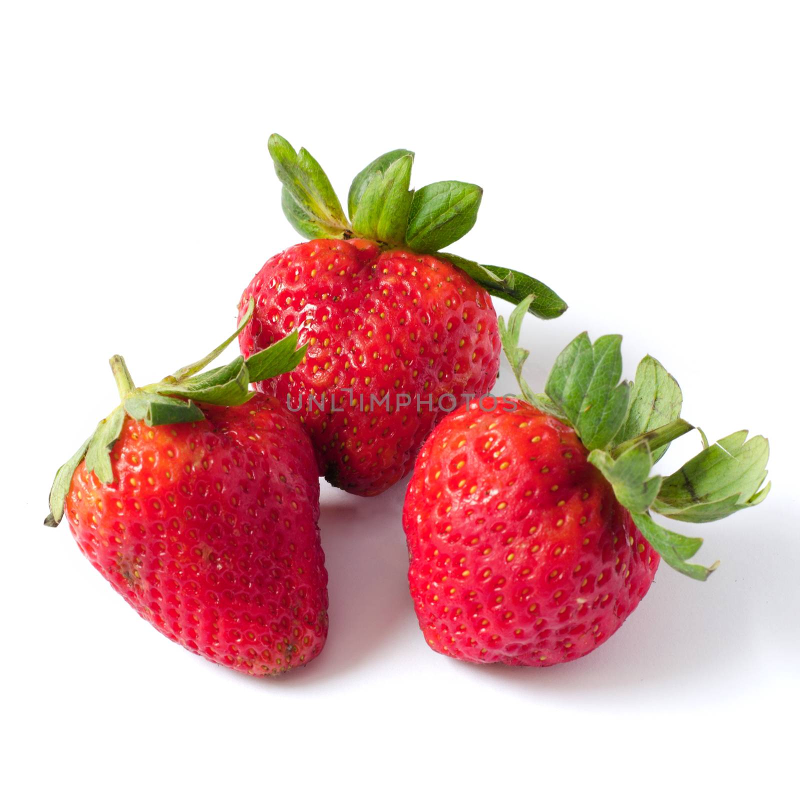 Three strawberries with leaves on a white by siraanamwong