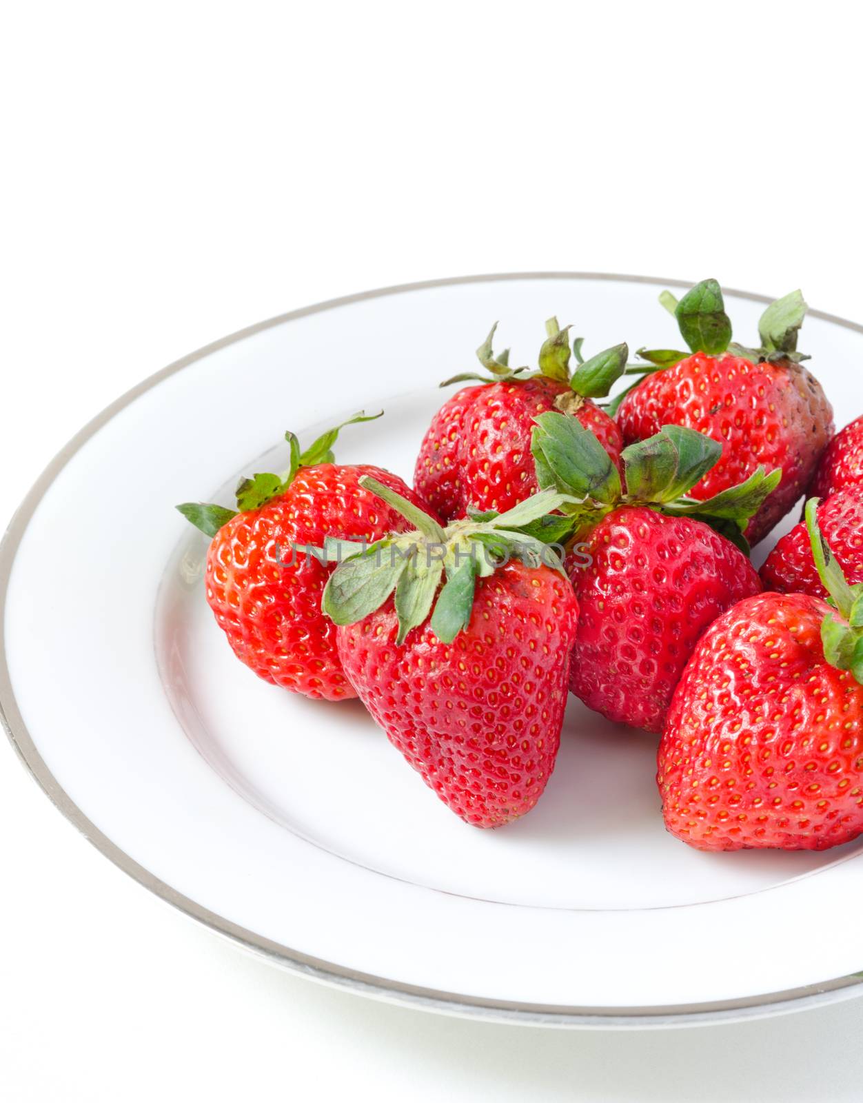 Ripe strawberries in a porcelain plate on white background