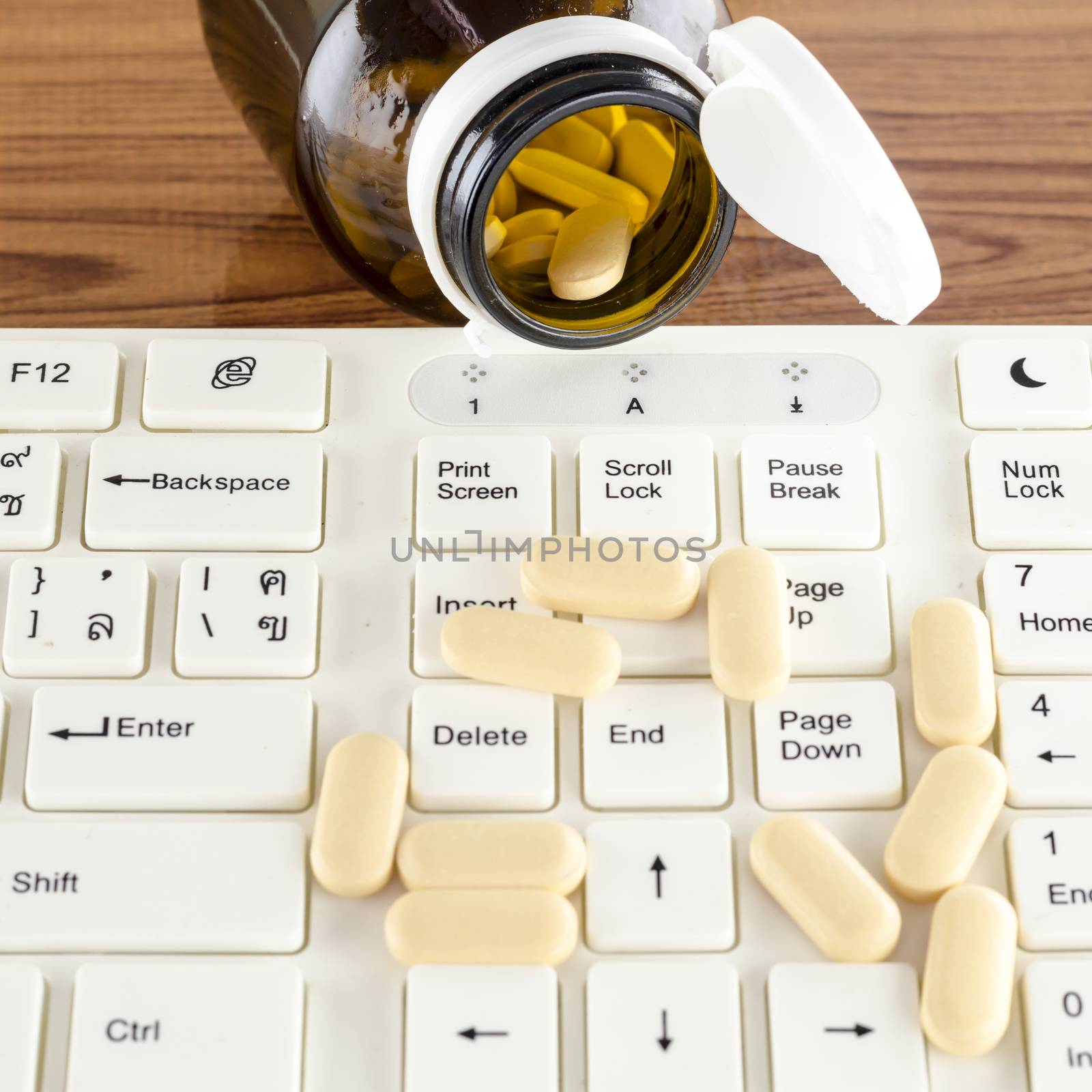 pills on keyboard computer on wooden background concept technology addiction