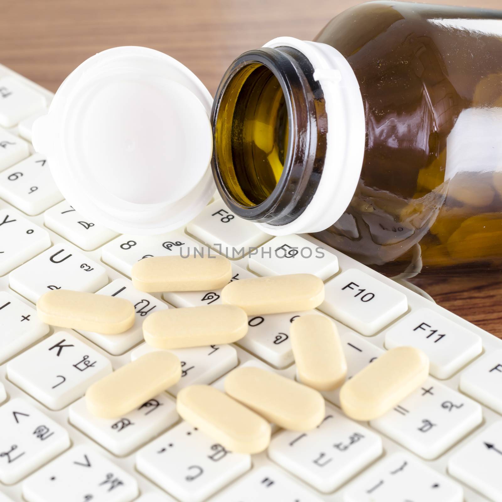 pills on keyboard computer on wooden background concept technology addiction