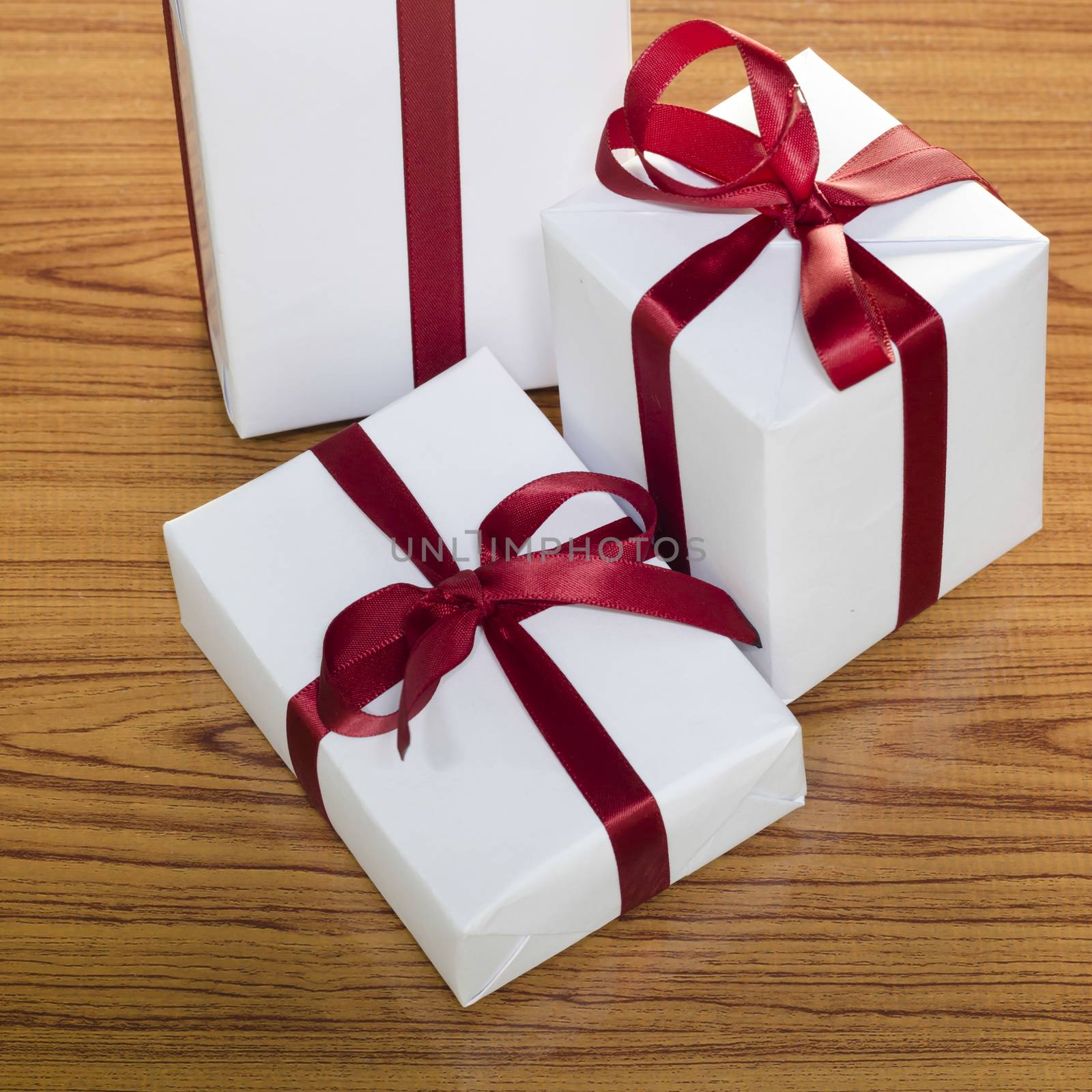 white gift box and red ribbin on wood background
