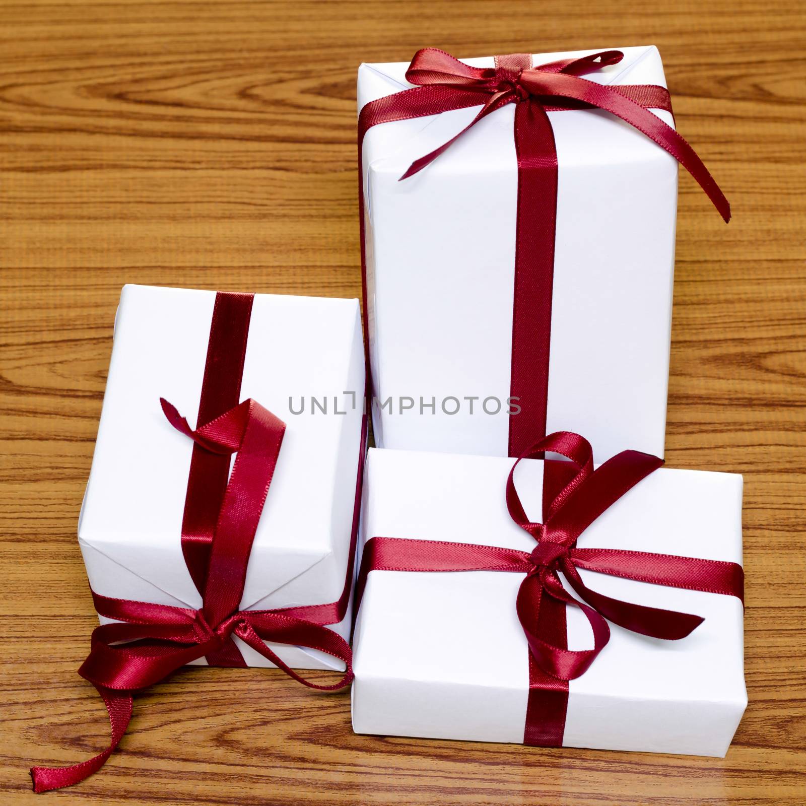 white gift box and red ribbin on wood background