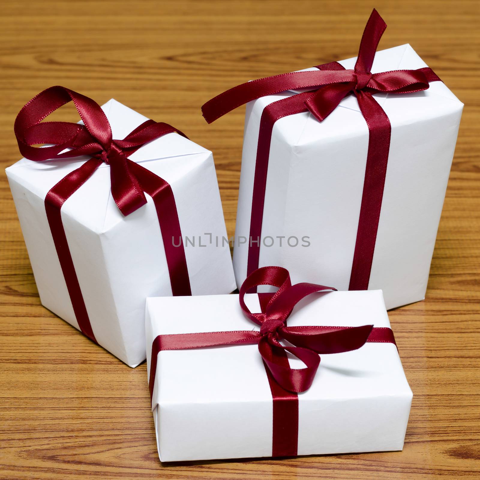 white gift box and red ribbin on wood background