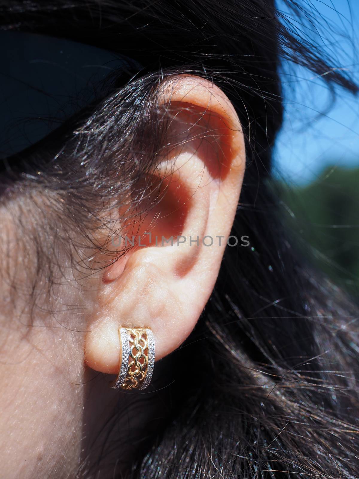 Earring with gold and diamonds at closeup in ear of a brunette