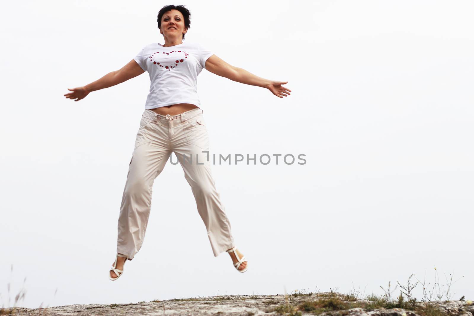 Adult smiling woman in white jumping outdoor