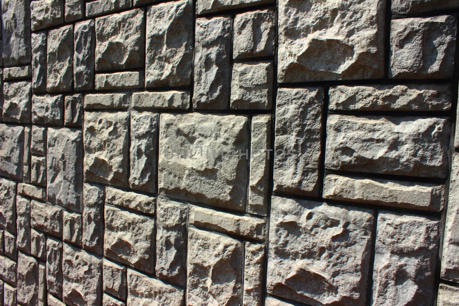 Gray wall of bricks of different shapes