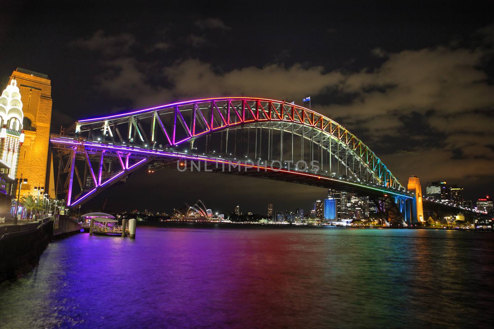 NTH SYDNEY, AUSTRALIA - JUNE 6, 2014;  Sydney Harbour Bridge in vibrant rainbow colours during the Annual Vivid Festival, view to Opera House and Circular Quay