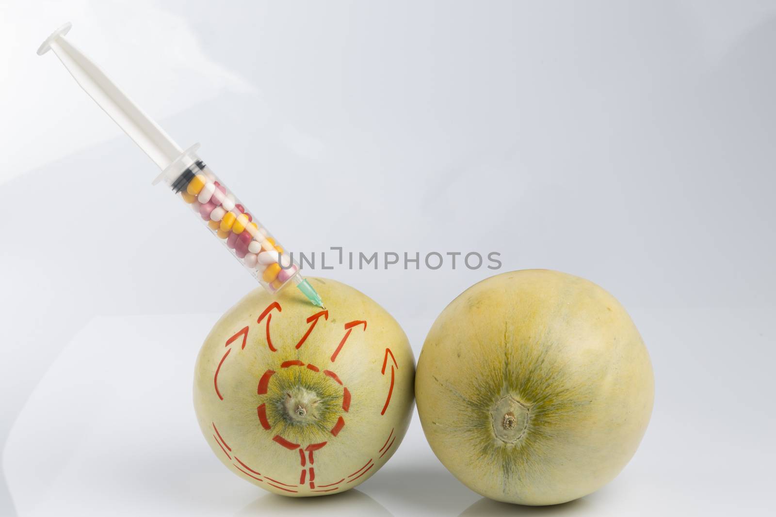 Cosmetic treatment  for Female breasts metaphor: melons with perforation lines whileand injected by a syringe with pillsmeaning cosmetic and health treatment