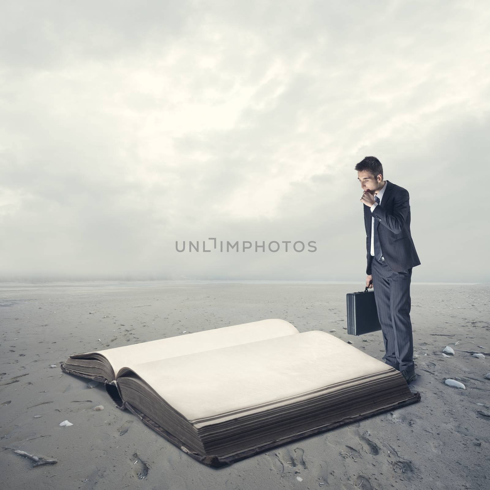 Businessman reading a huge old book in the desert.