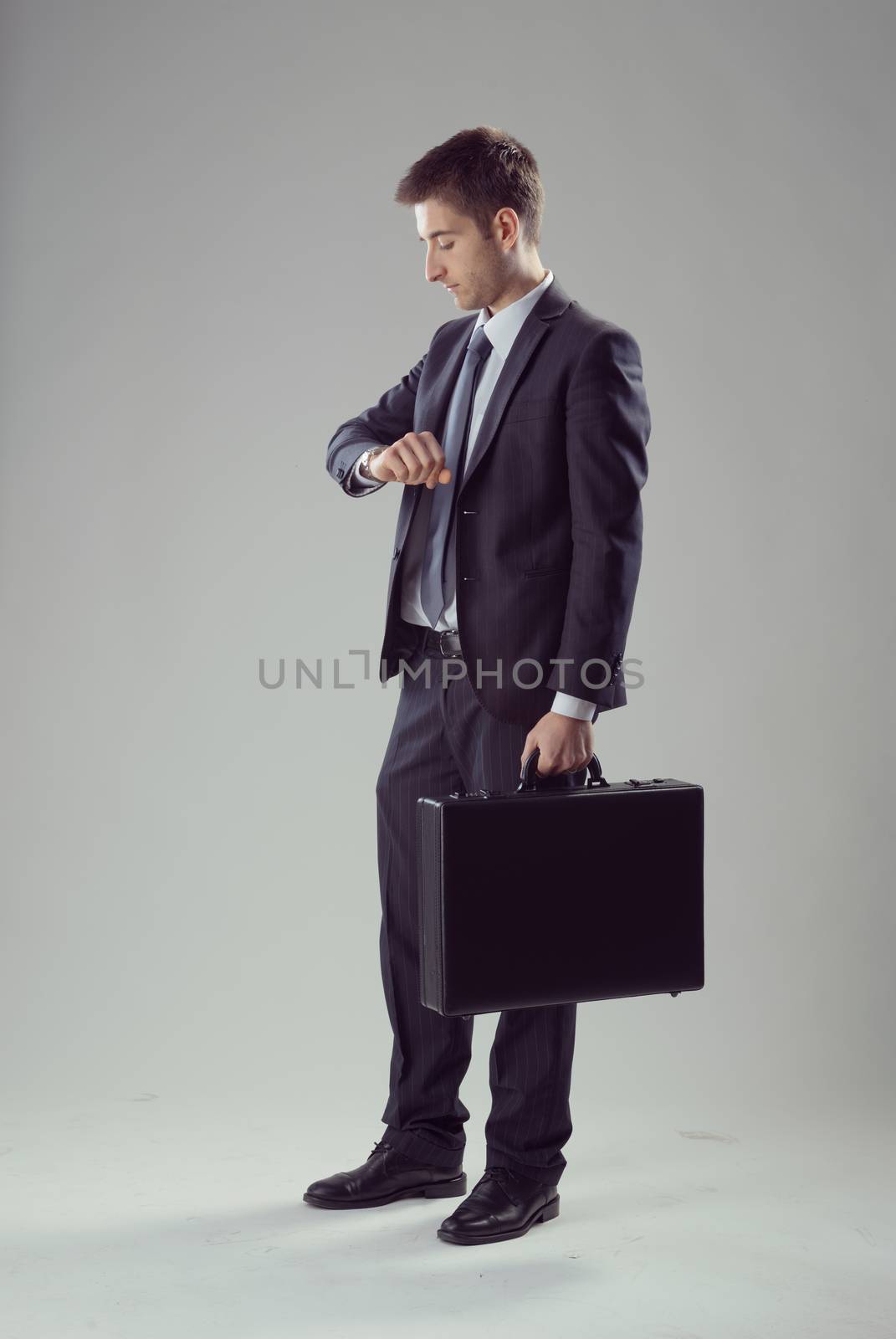 Young elegant businessman waiting with briefcase checking the time.